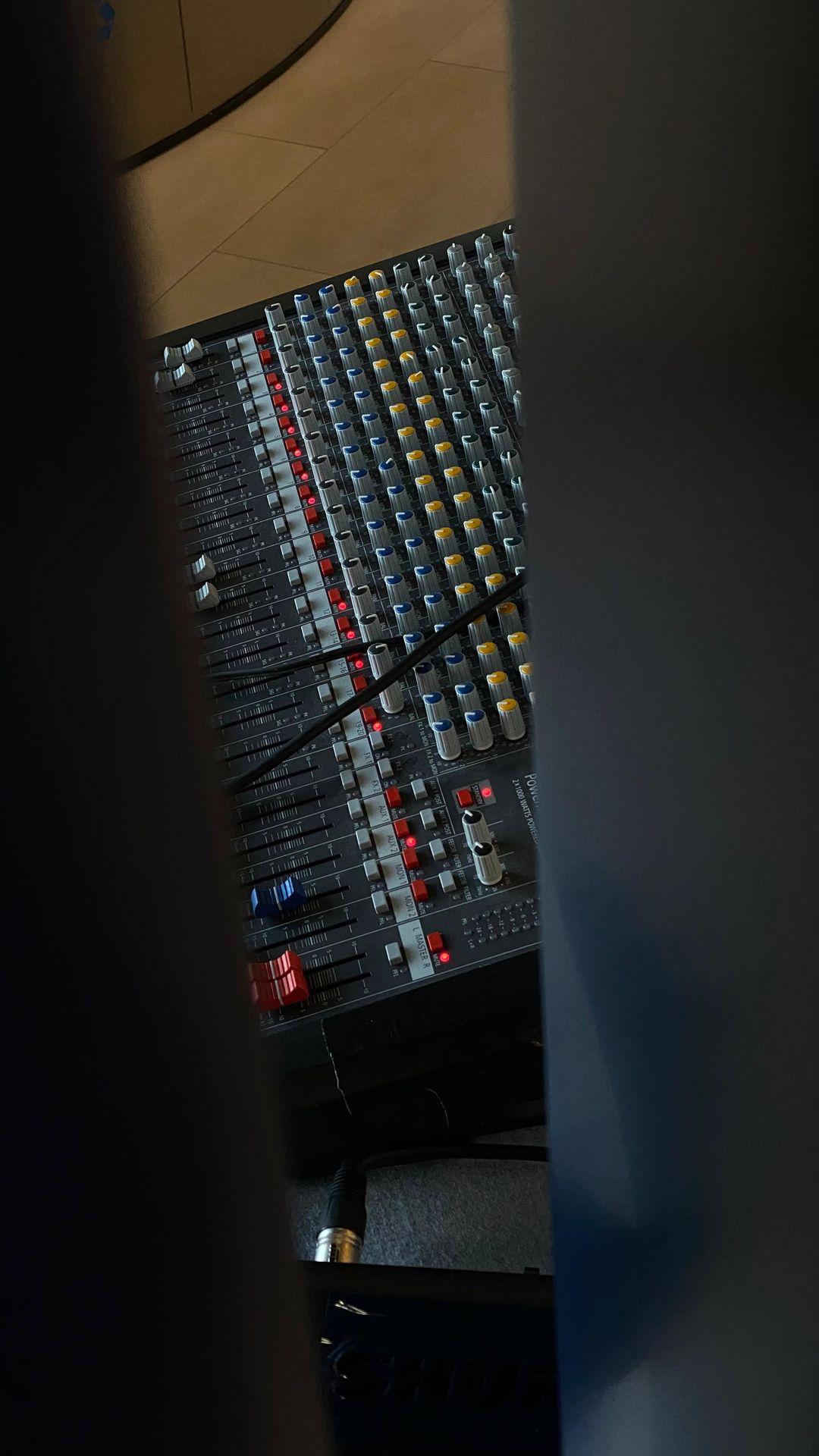 Close-up view of a professional audio mixing console with various knobs, sliders, and cables.