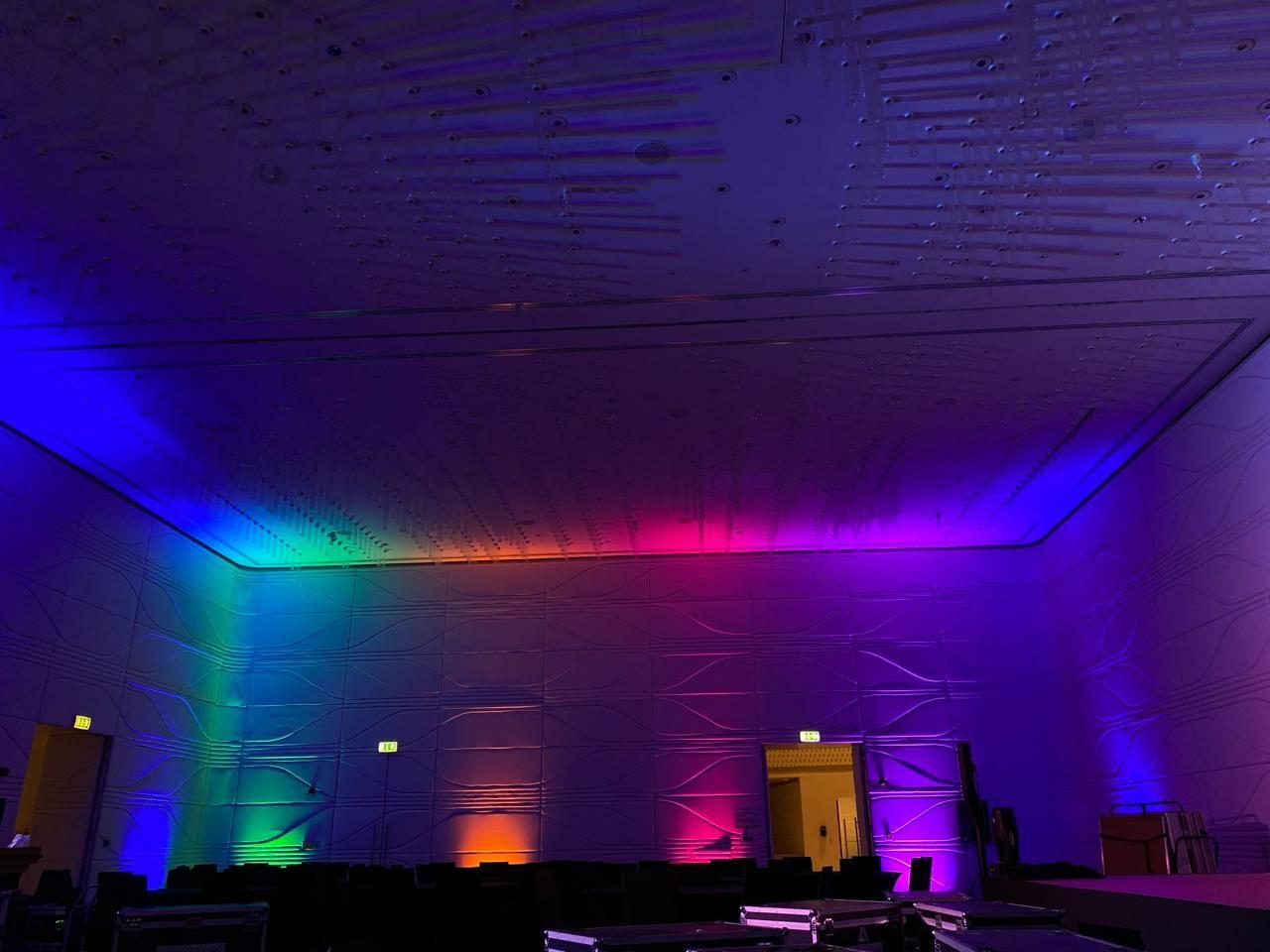 Large room with walls illuminated by rainbow-colored lights.